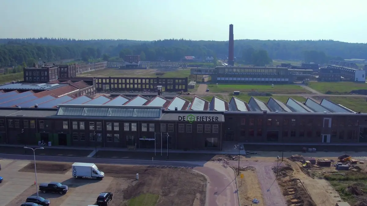 Luchtopname van De Fietser in de ENKA-Westhal met de oude fabrieksschoorsteen